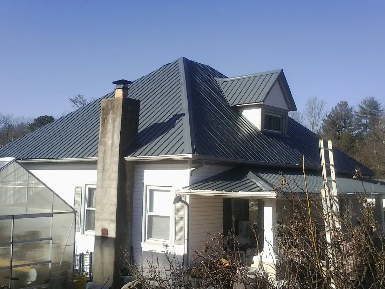 Dark blue standing seam metal roof on a white farmhouse with dormer — Slate & Tile Roof Repair by Roofing Brothers in Carson City
