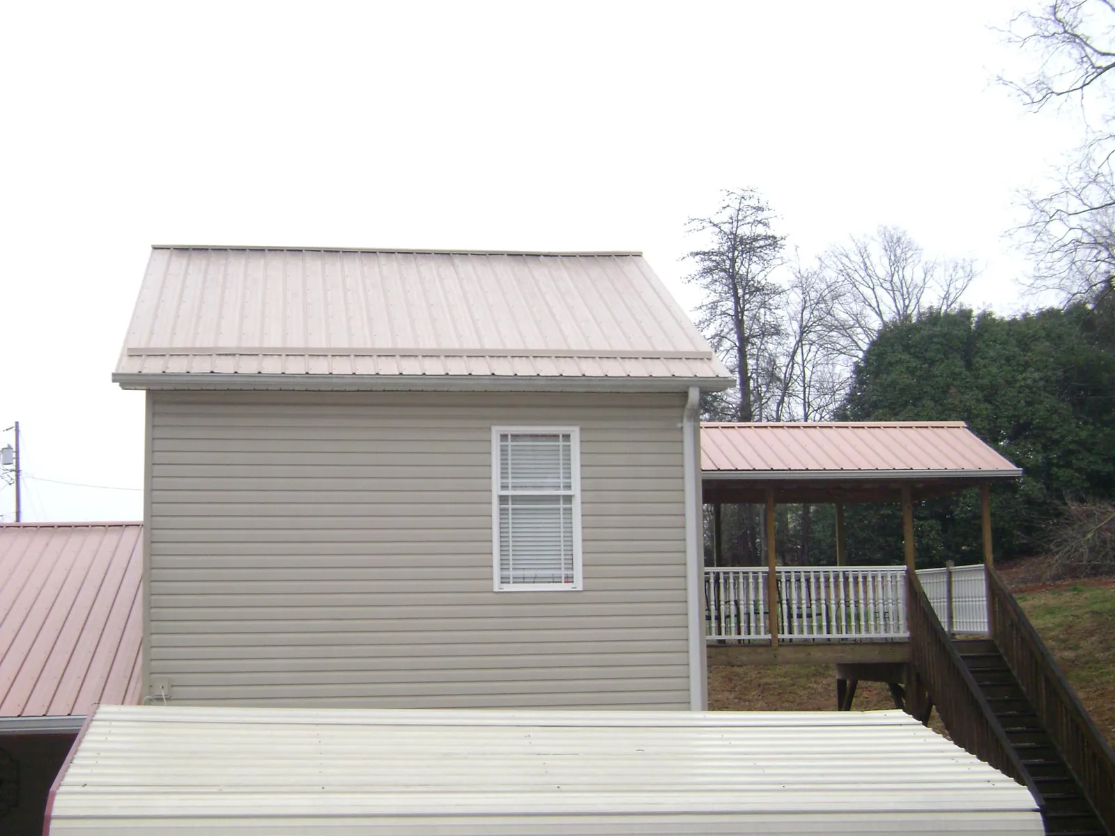 Tan metal roofs on a two story addition and attached porch, from a Roof Replacement job in Carson City
